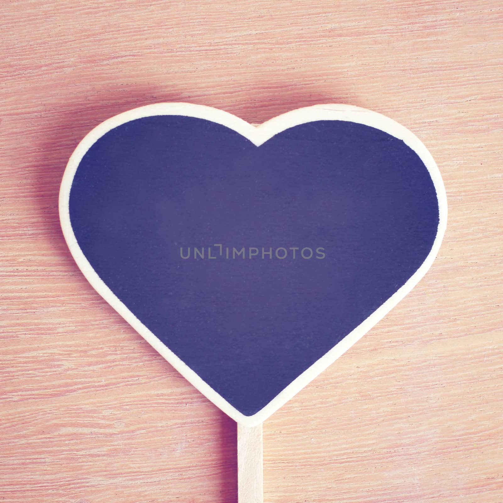 Heart shaped blackboard on wooden background with copy space, retro filter effect 