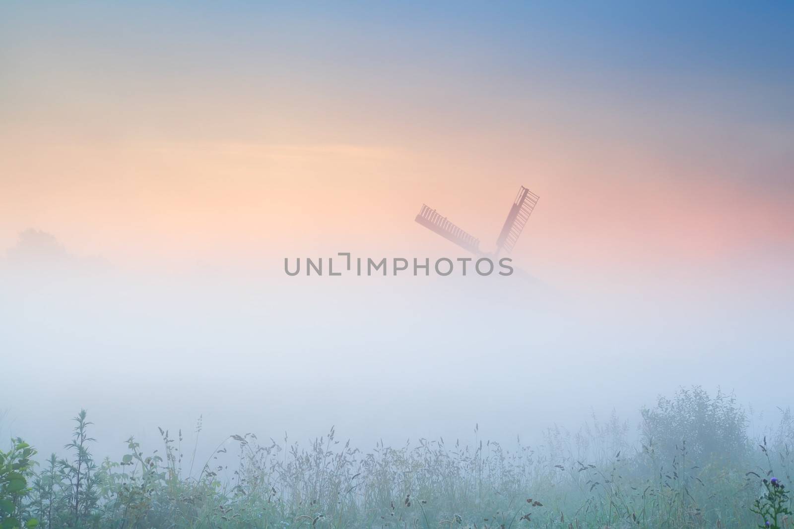 windmill in dense fog at sunrise by catolla