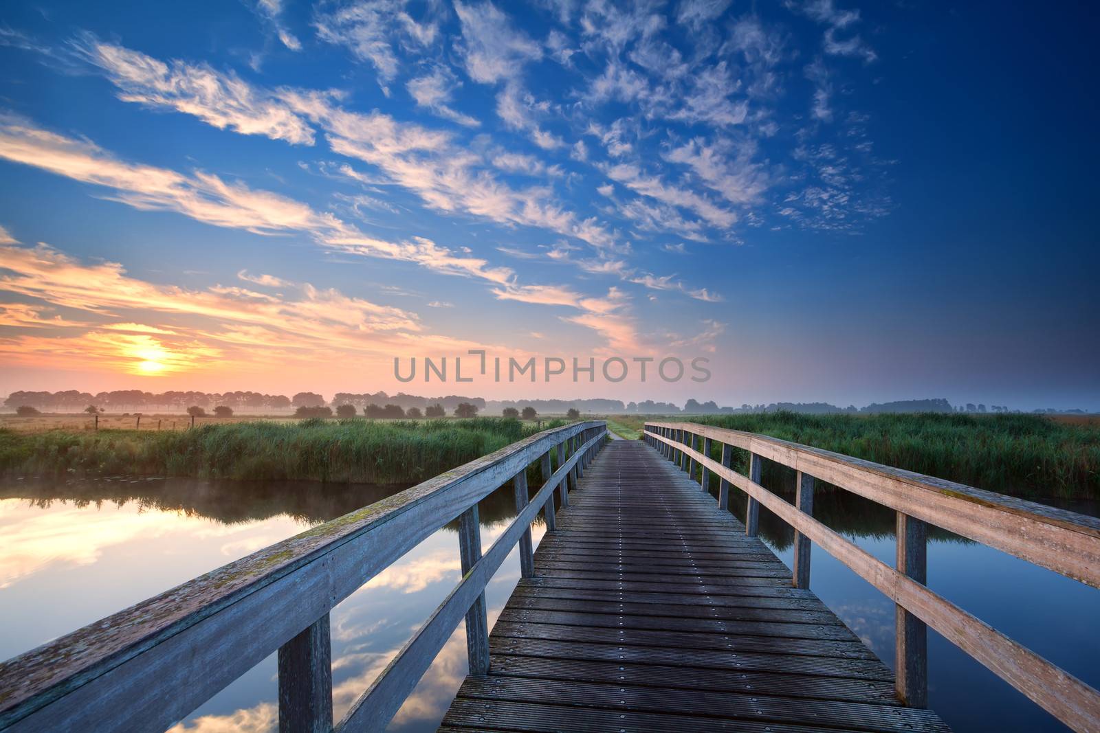 wooden bridge over river at summer sunrise