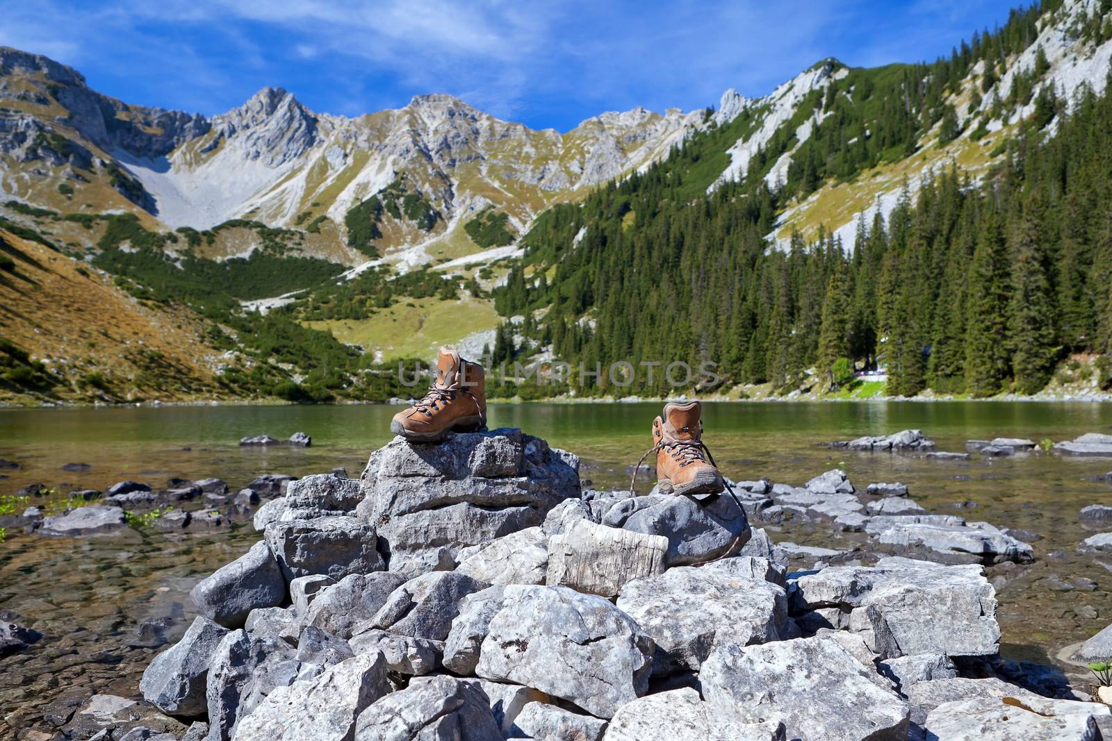 female leather hiking shoes on rock by Alpine lake, Bavaria, Germany