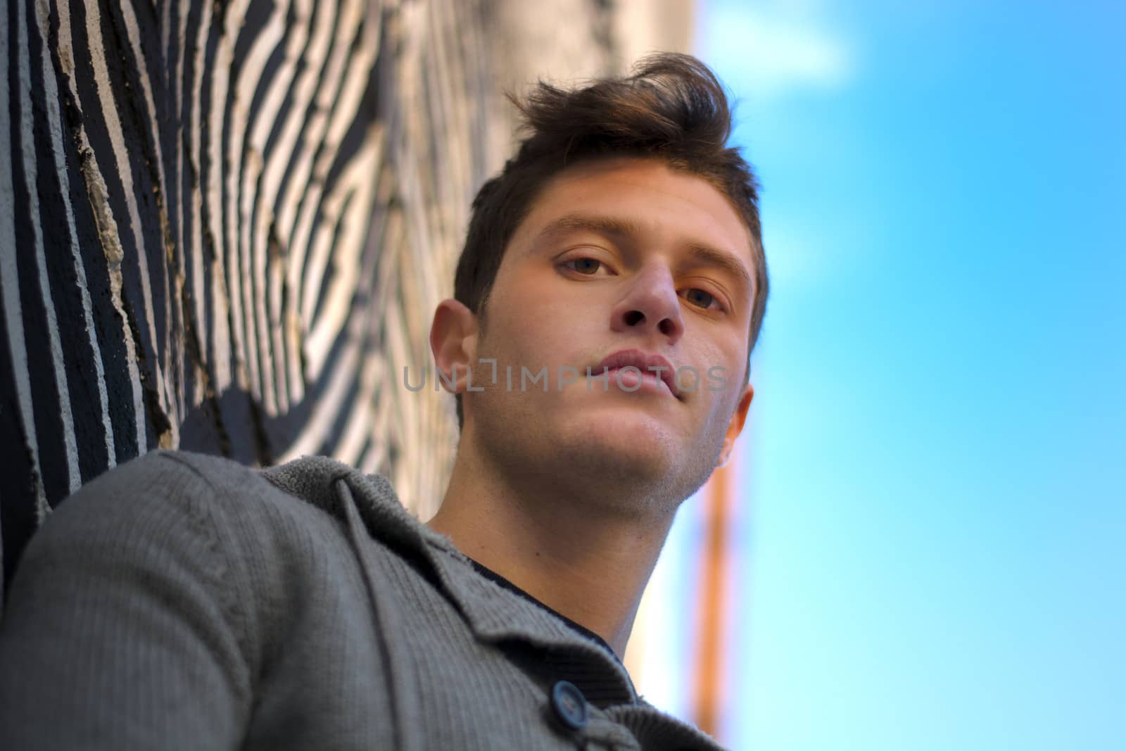 Handsome young man against zebra striped design in urban setting, looking at camera
