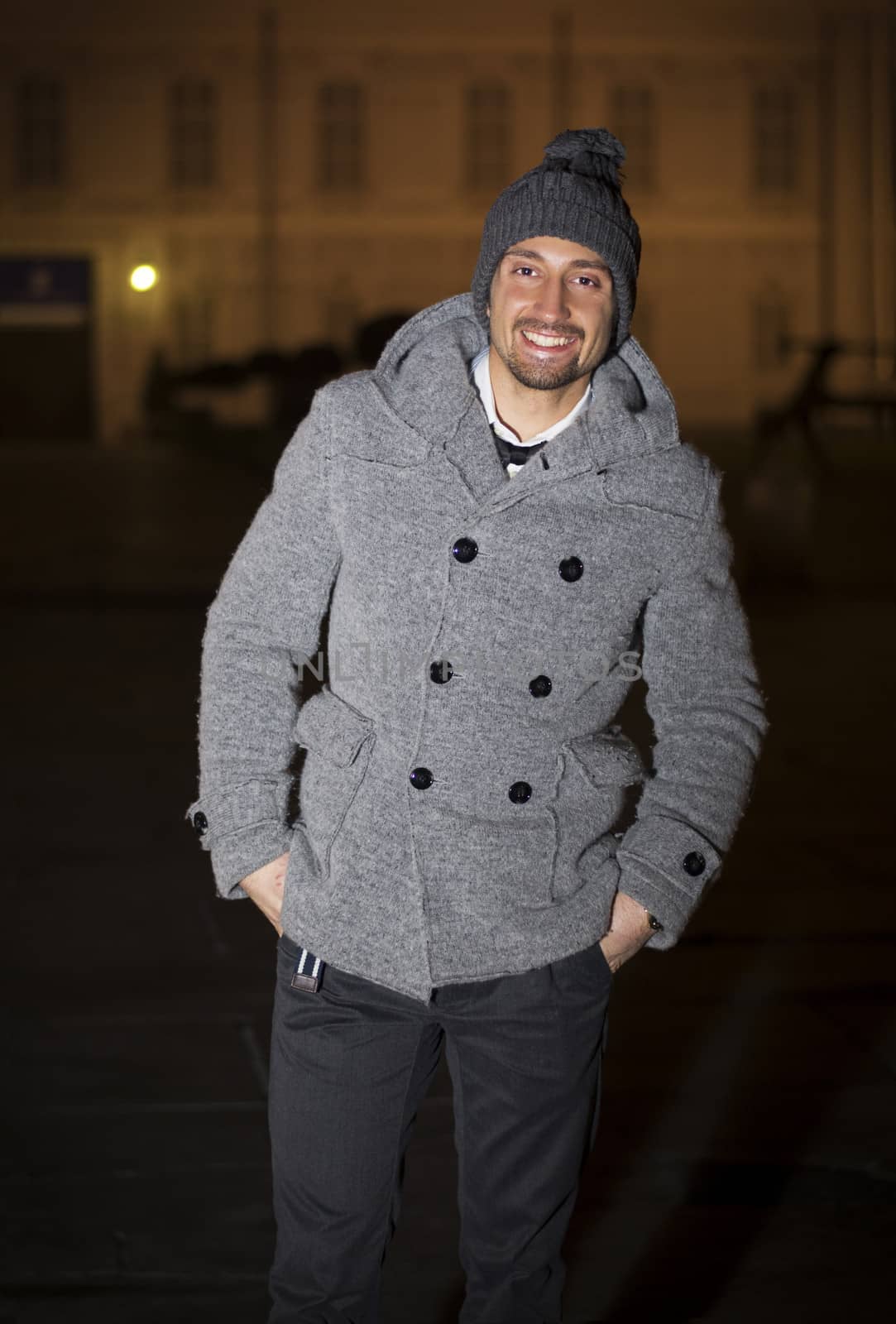 Attractive young man at night in Piazza Castello in Turin, Italy, wearing wool hat and coat