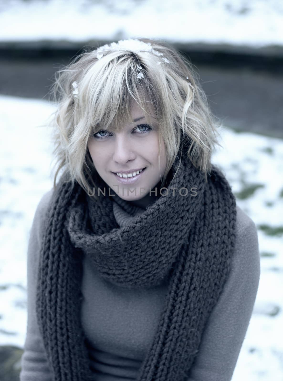 Attractive blonde young woman with wool scarf, snow around her