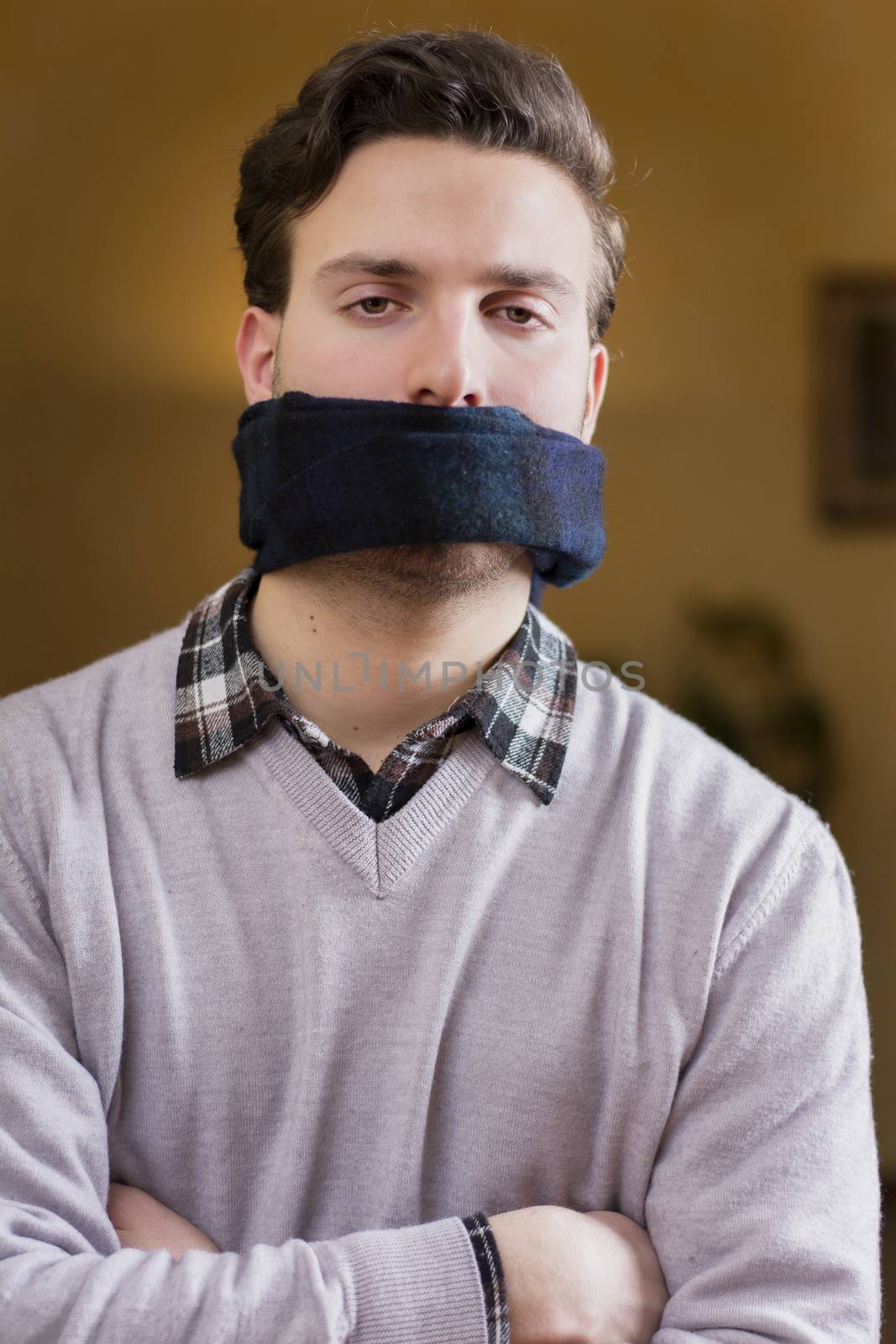 Young man with gag (scarf) on his mouth cannot speak