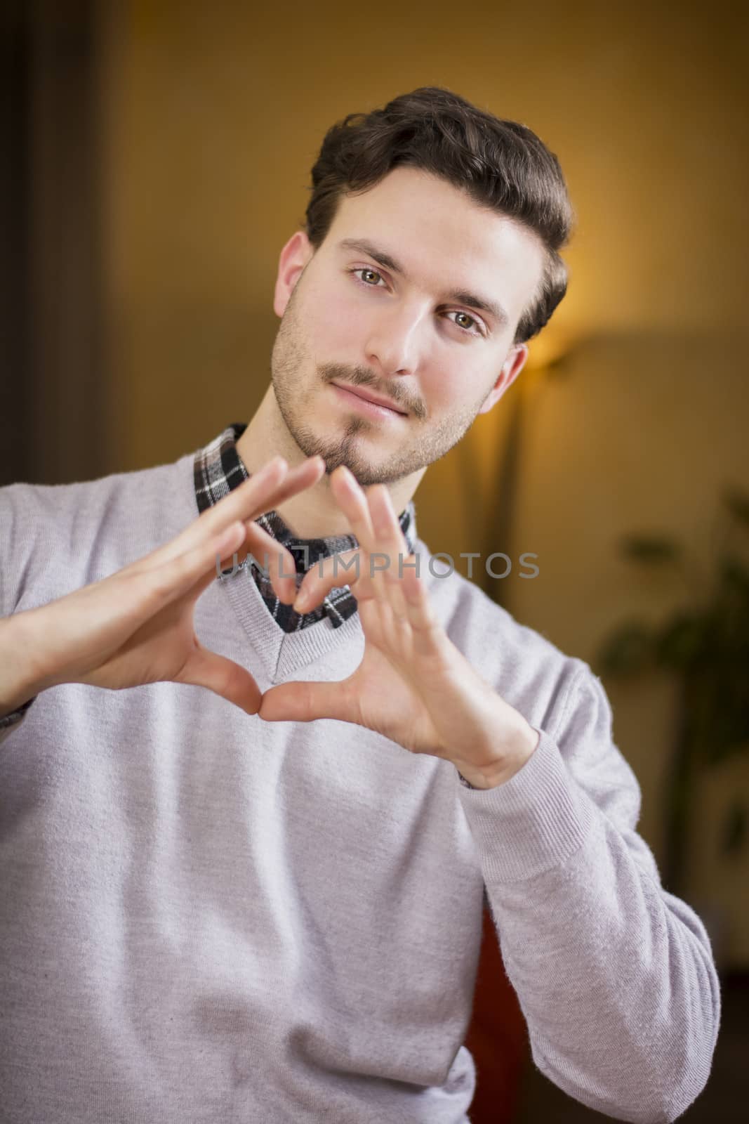 Handsome young man making heart sign with hands, a heart with his fingers