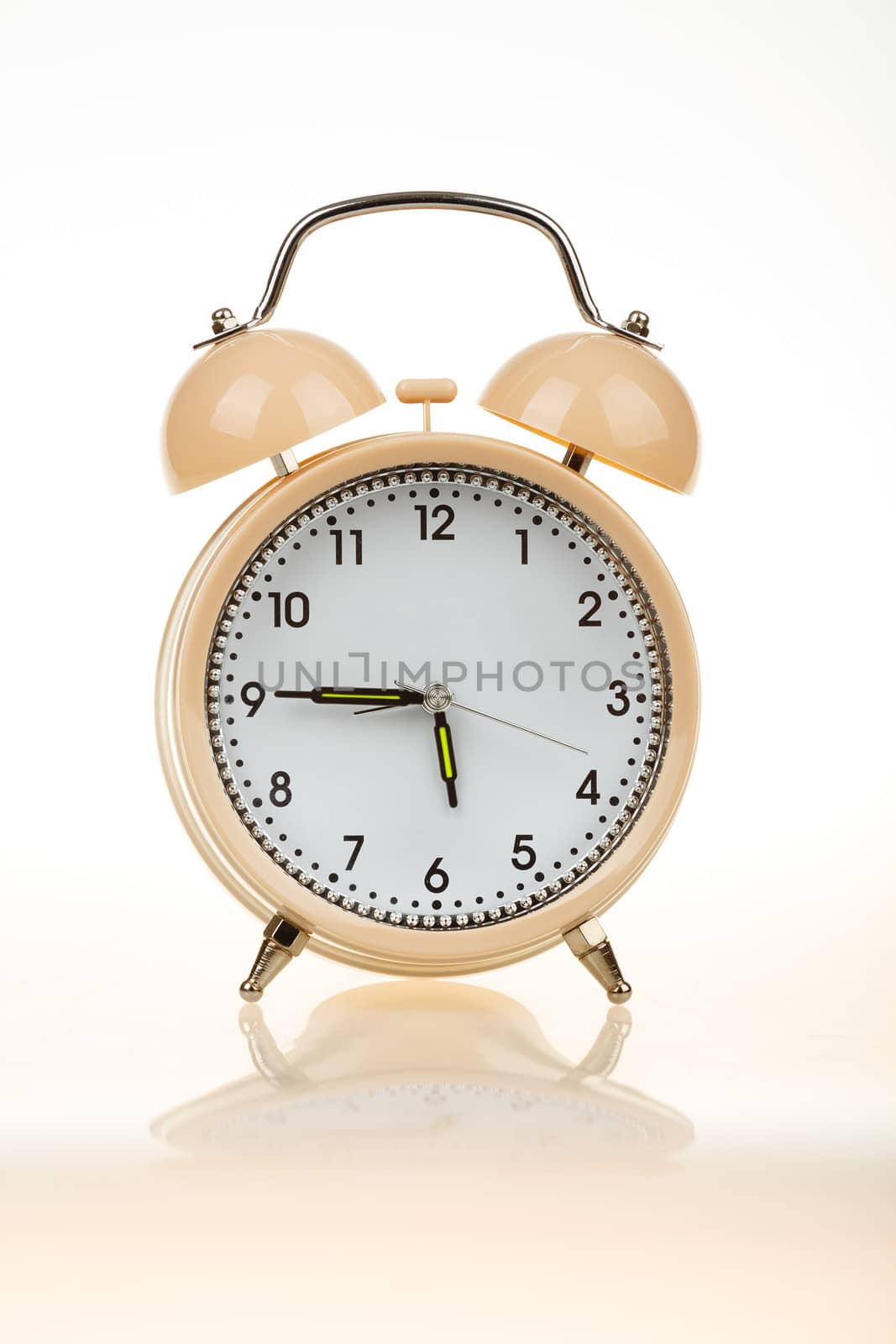classic alarm clock on white table with reflection