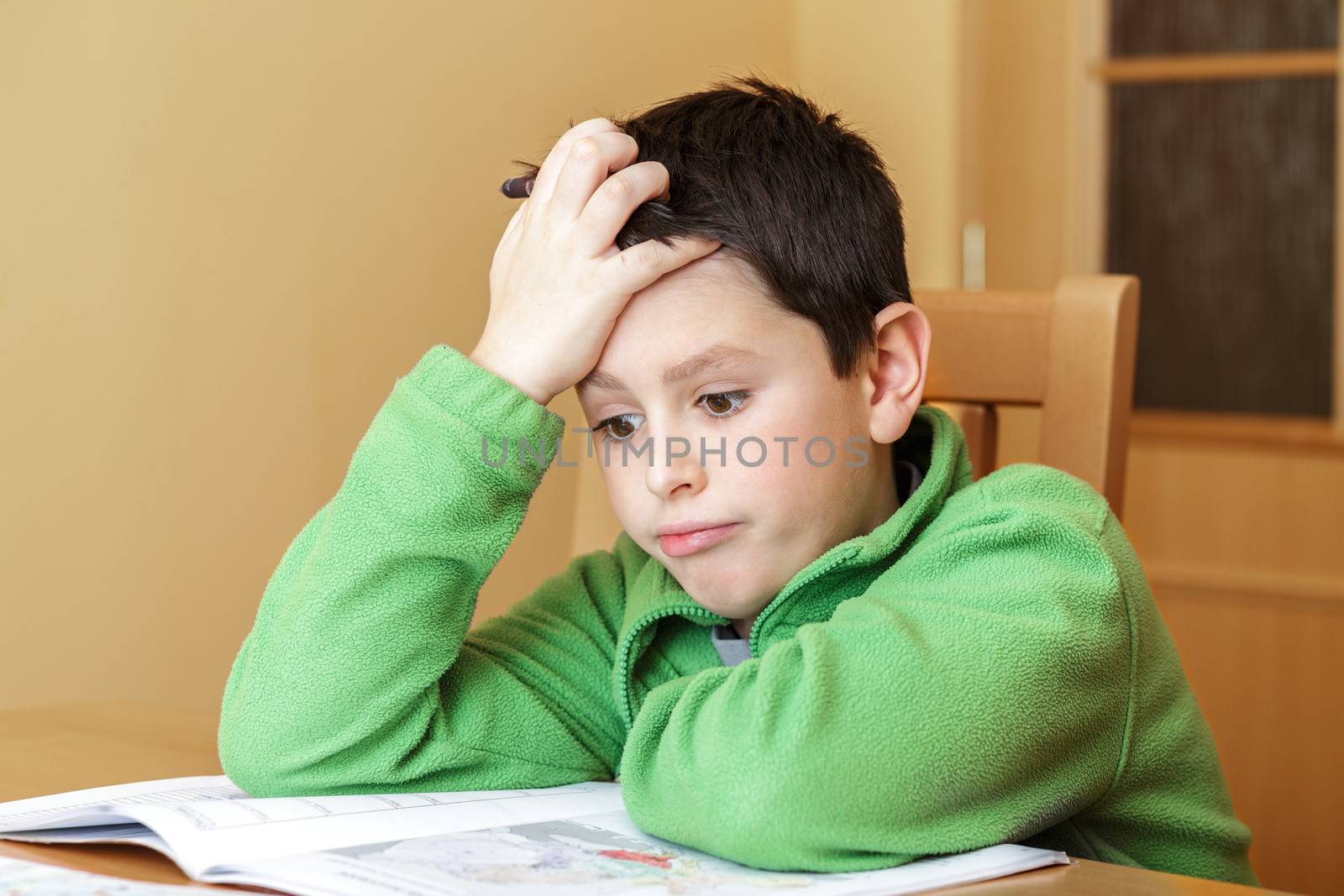 bored and tiredboy doing homework from school in workbook using worl map