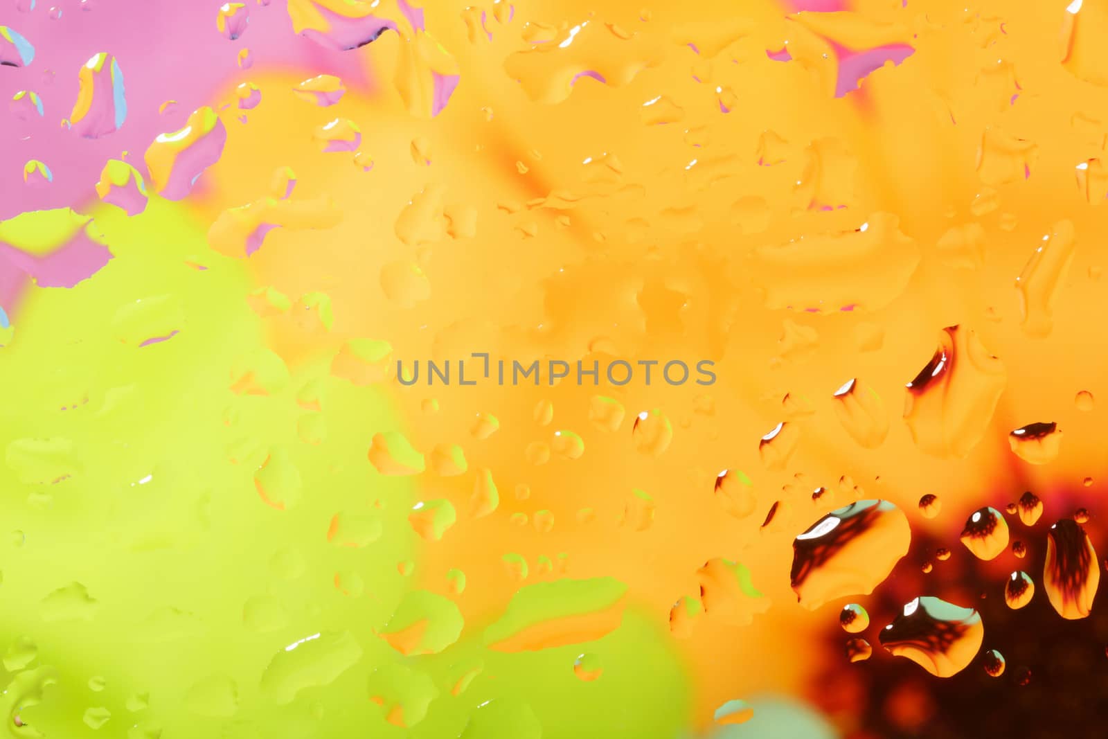 color abstract background with water drops on glass with flower in background 