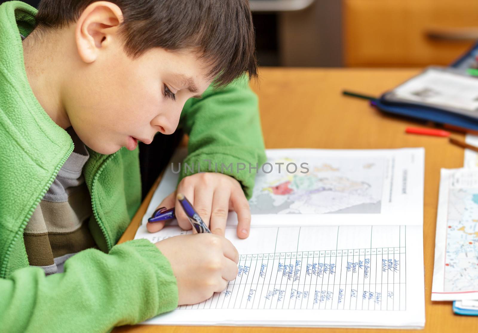 bored and tiredboy doing homework from school in workbook using worl map