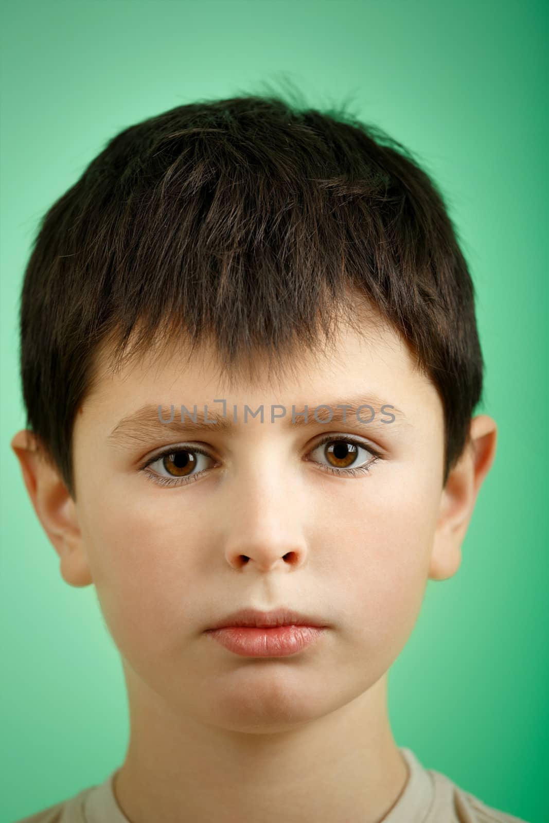 studio portrait of young boy on green background