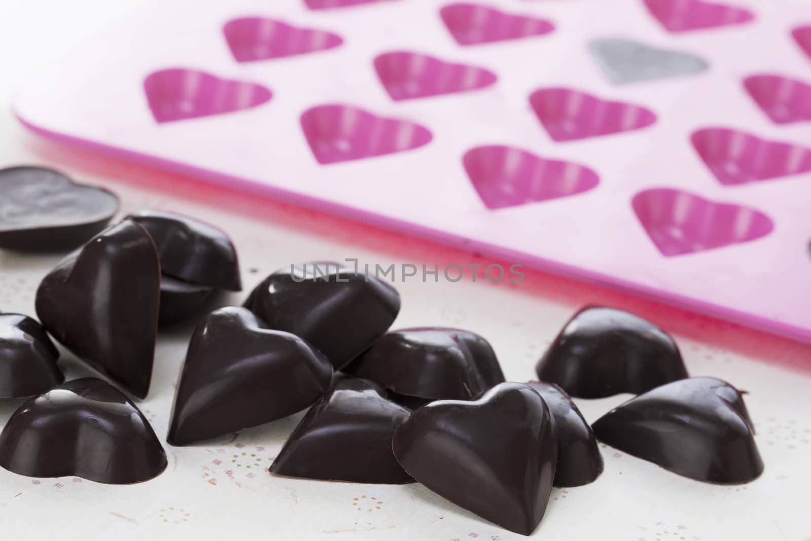 Dark chocolate hearts in with heart form in background
