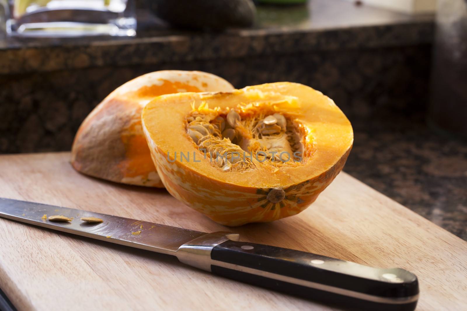 Winter squash cut in half with knife on cutting board.