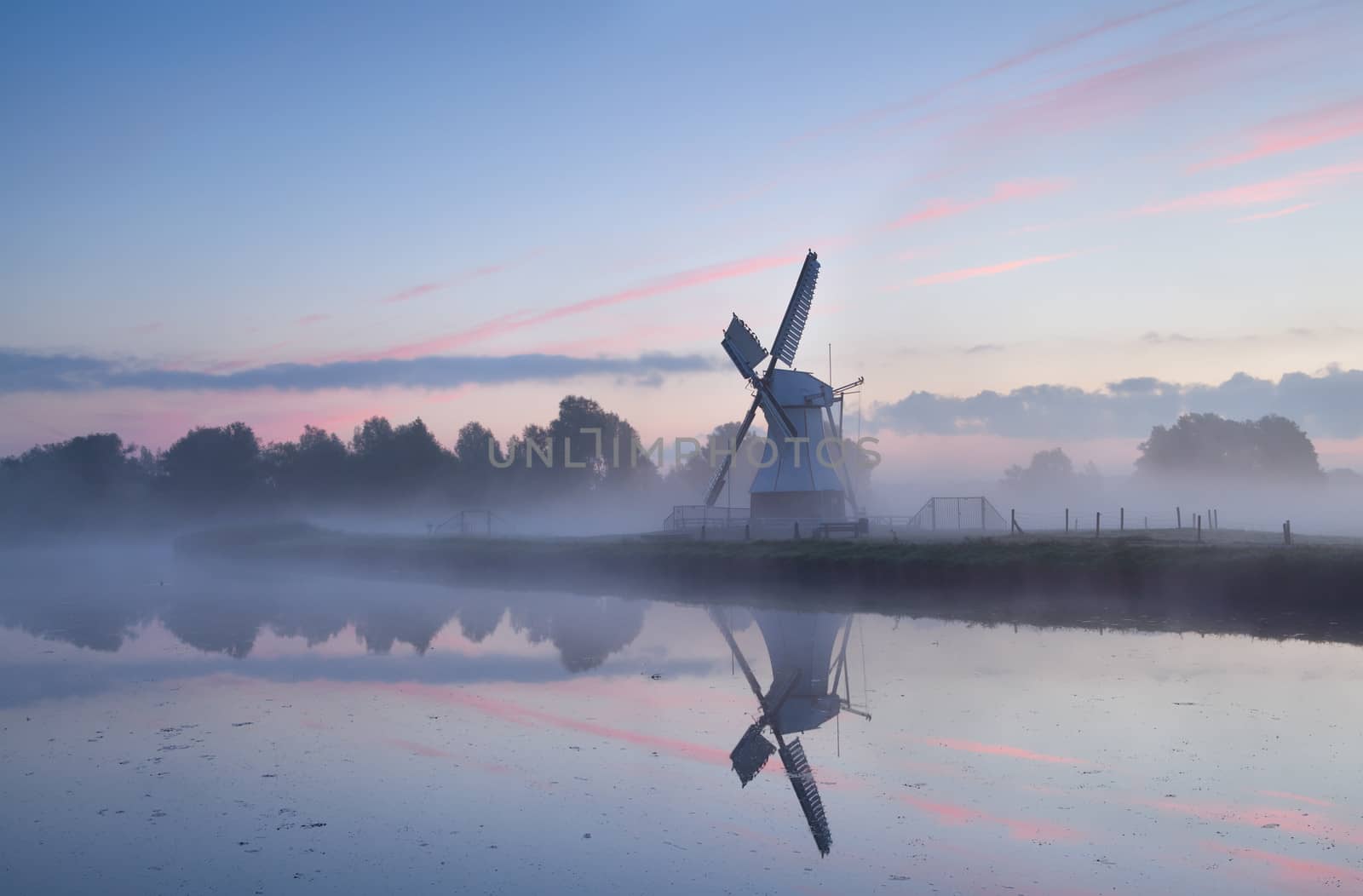 charming Dutch windmill in morning mist at sunrise by catolla