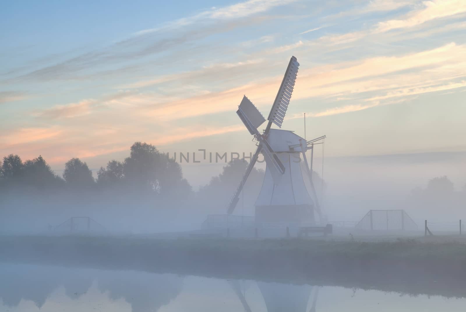 Dutch windmill in morning fog at sunrise, Holland