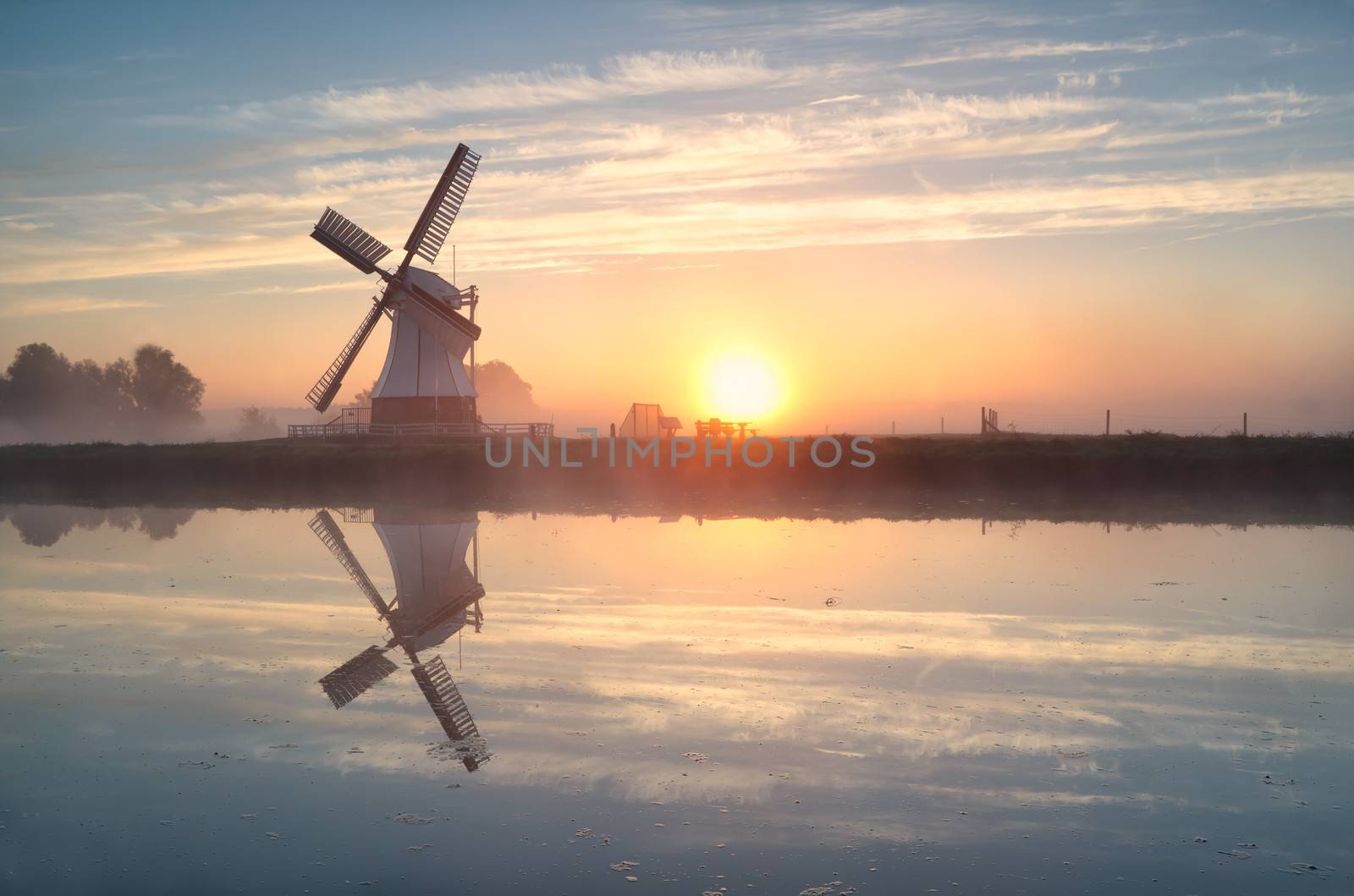 Dutch windmill reflected in river at sunrise, Groningen, Netherlands