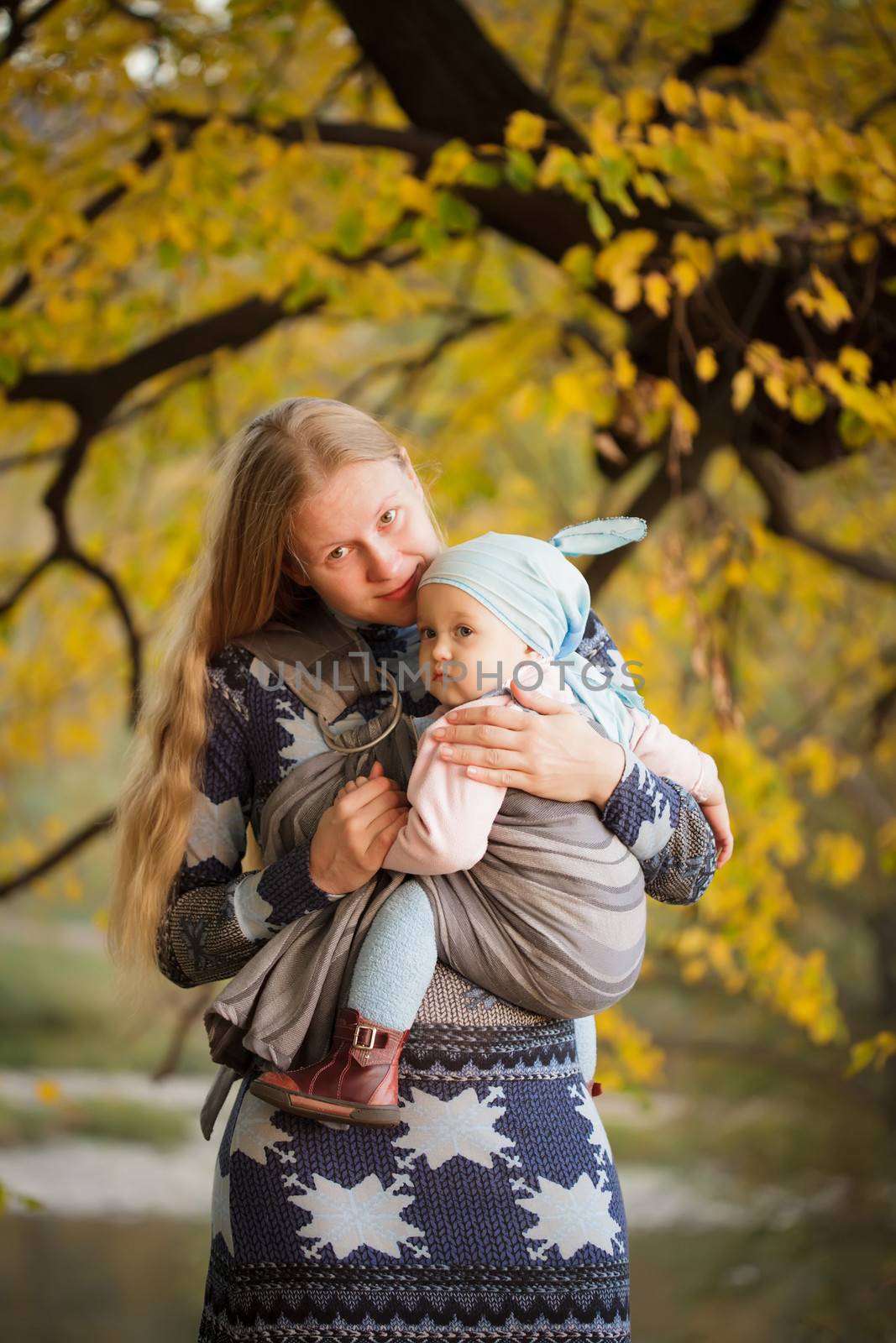 Mother walking with  baby in sling in the park
