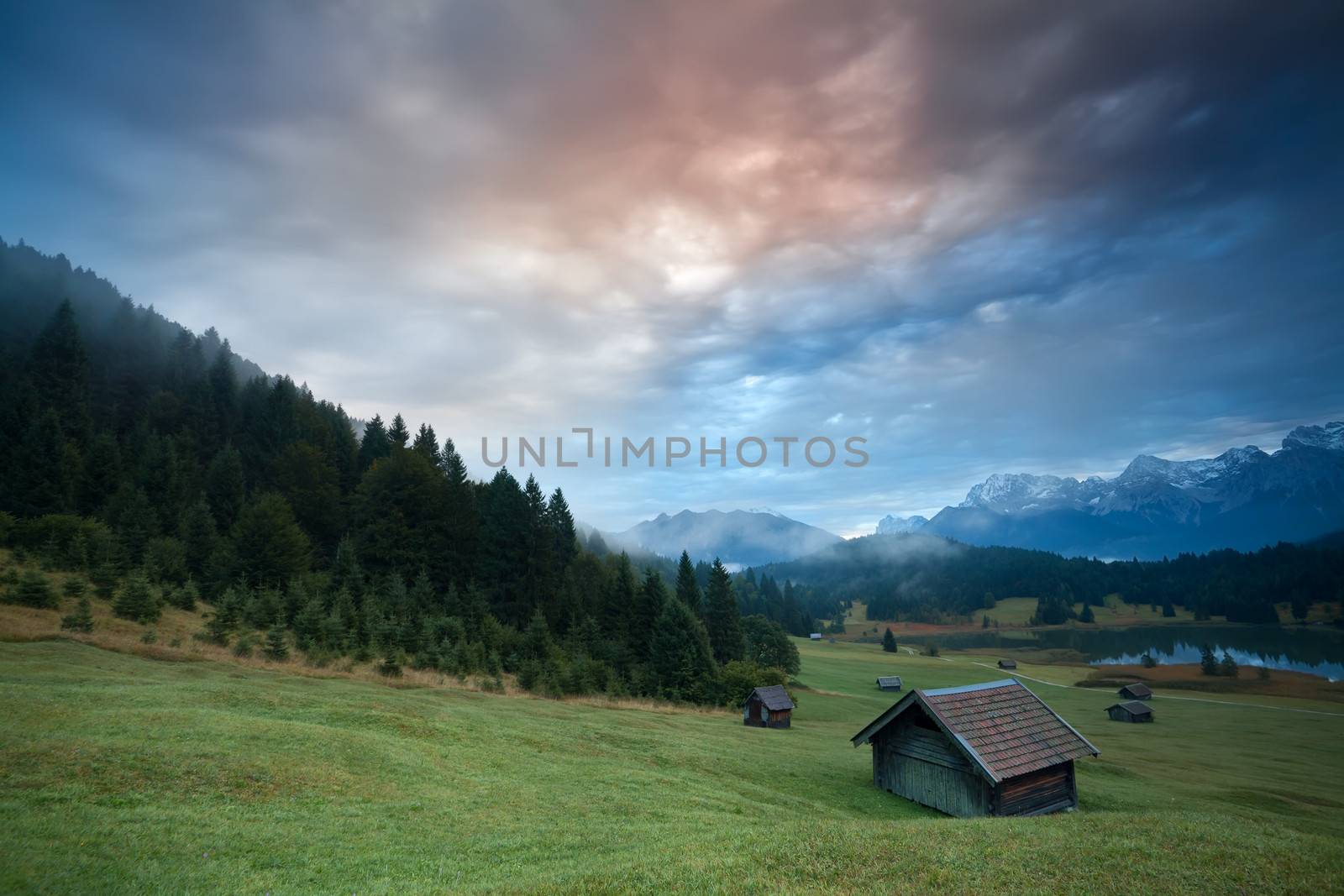 misty sunrise over huts by Geroldsee lake in Bavarian Alps, Germany