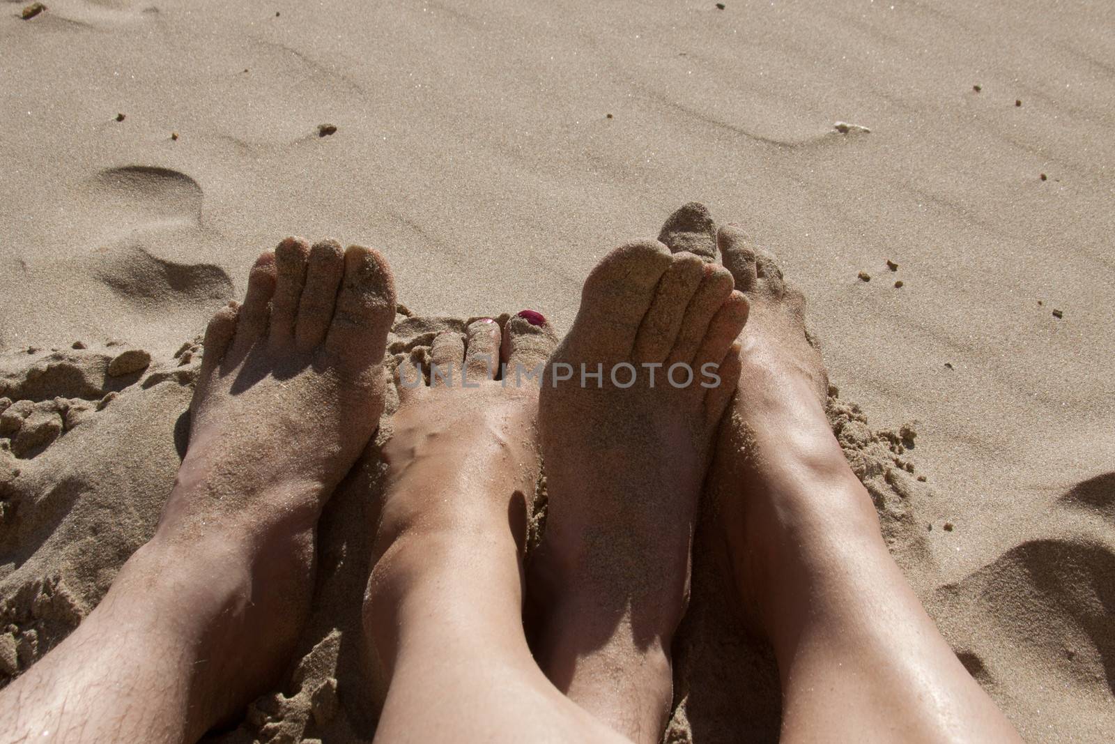 Sandy feet on the beach showing a couple is enjoying their vacation on the beach.