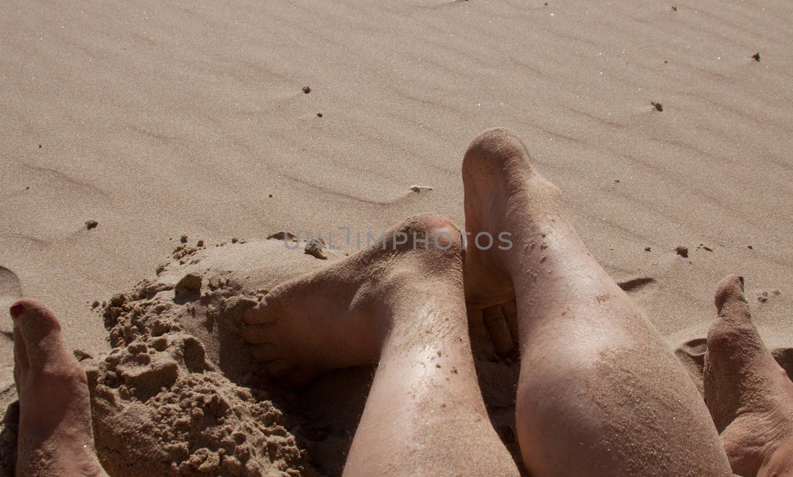 Sandy feet showing a couple enjoying the beach on their vacation.