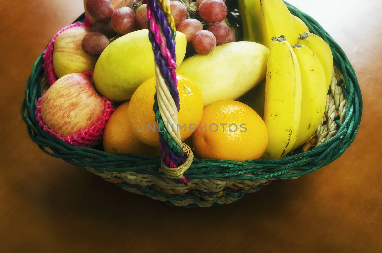 Gift fruit basket filled with grapes, apples, mangoes, bananas, and oranges