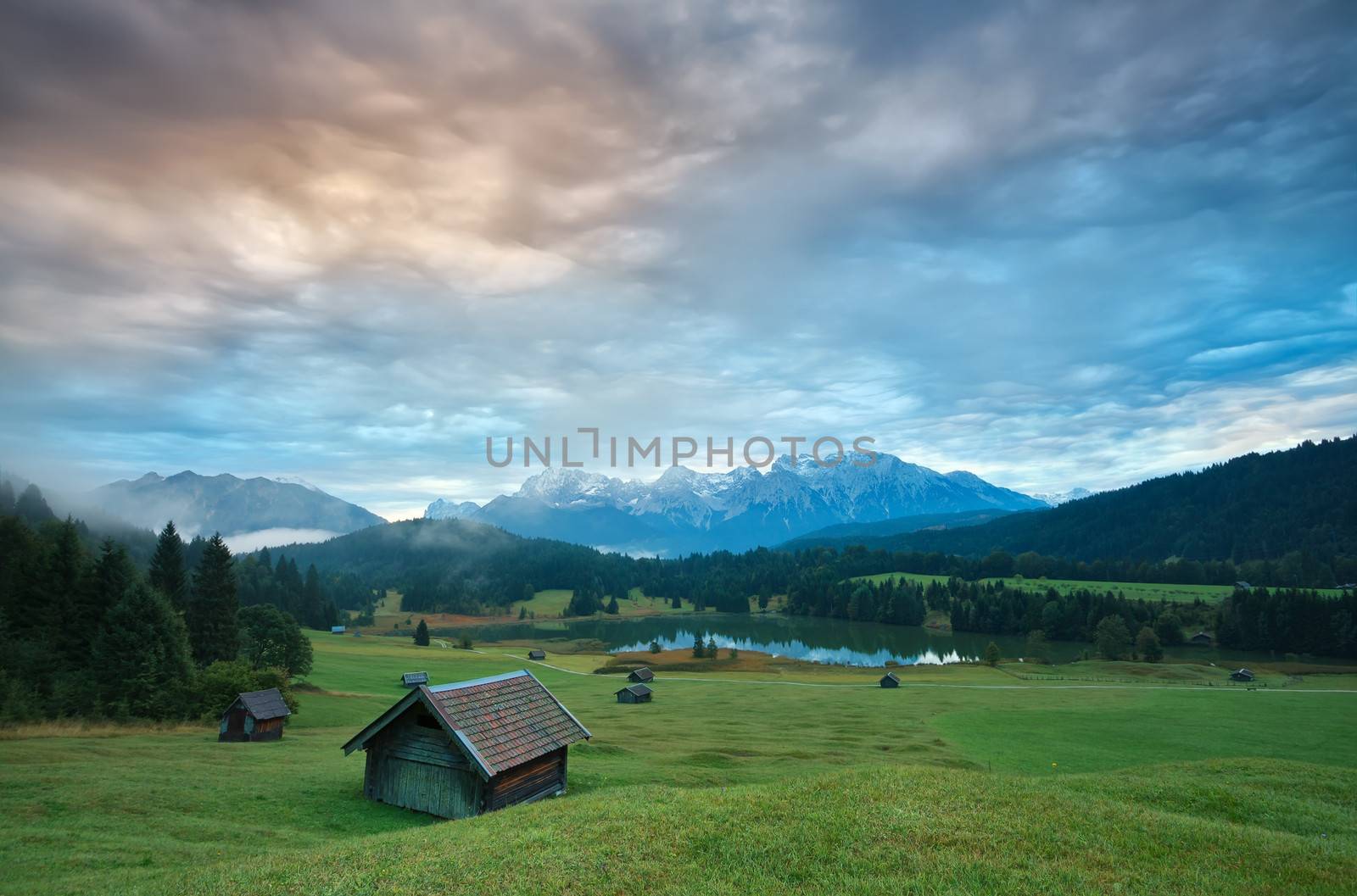 wooden hut o meadow by Geroldsee lake at sunrise, view on Karwendel Alps