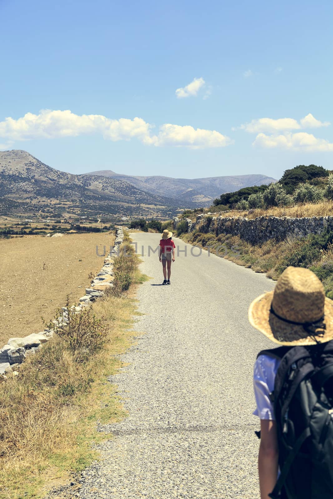two teenager walking on a street in mediterranean landscape .