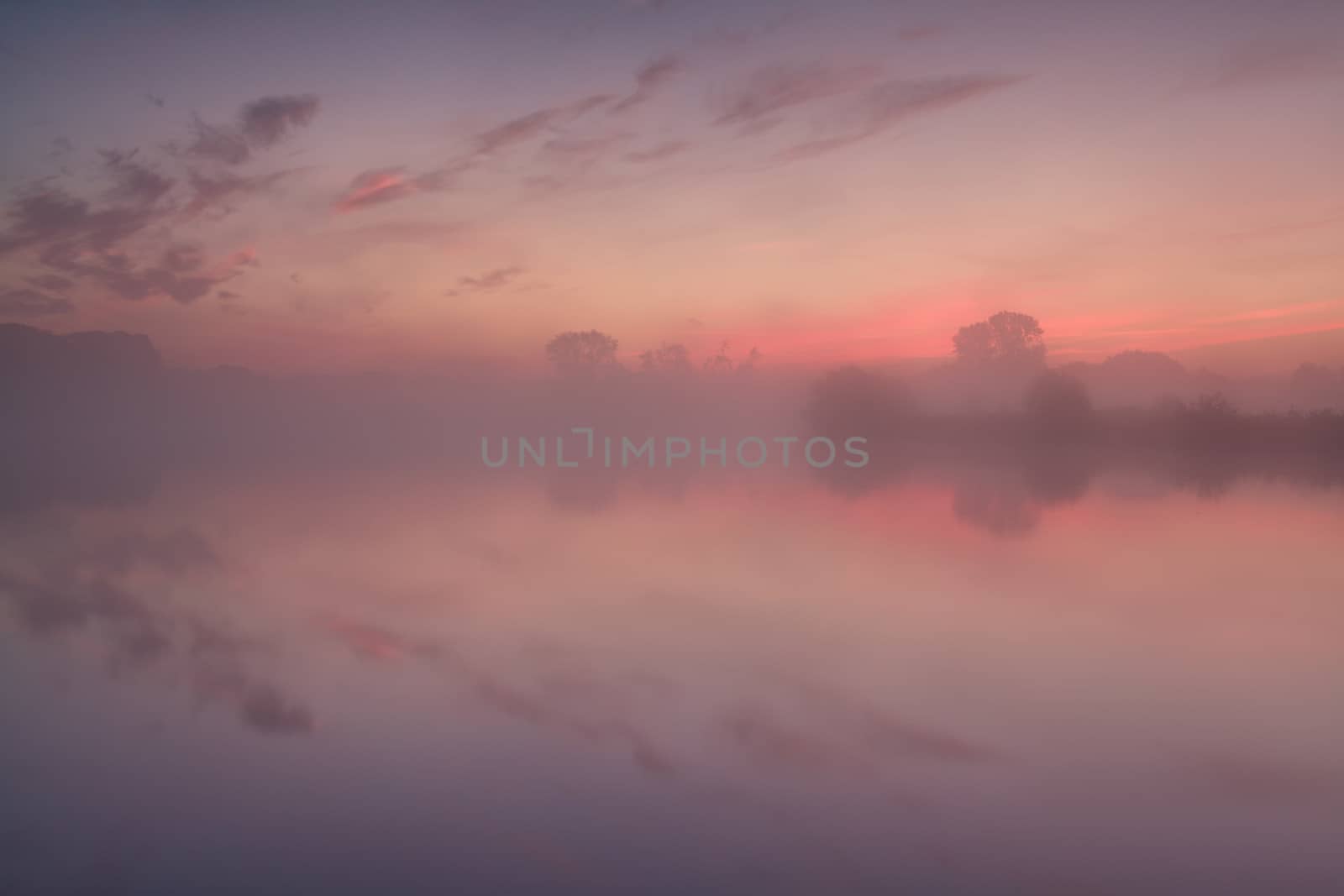 dense fog over lake at dramatic red sunrise, Netherlands