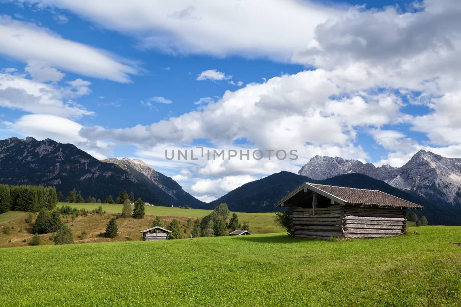 few huts on greem meadows over blue sky in Bavarian Alps