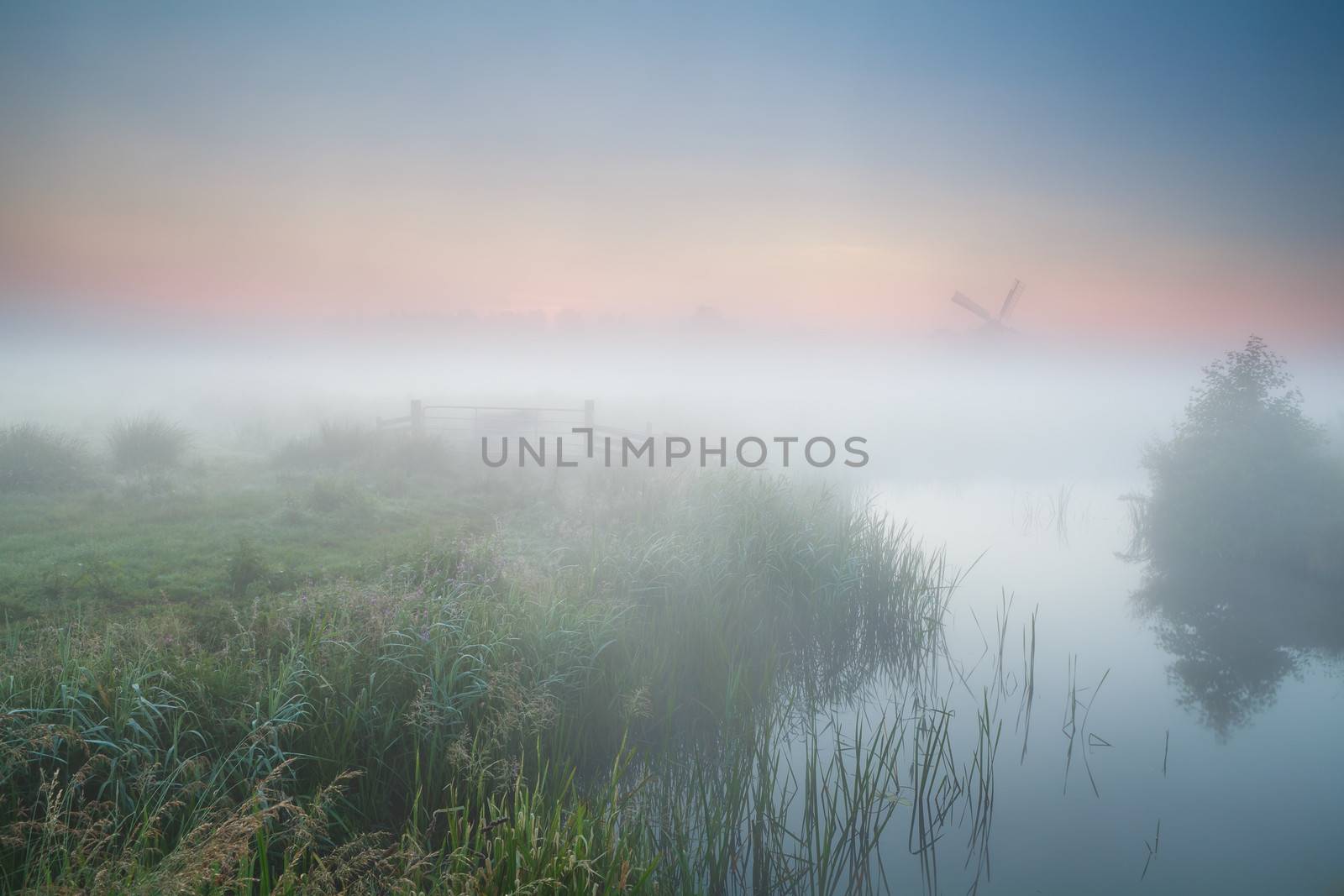windmill and river in morning fog by catolla