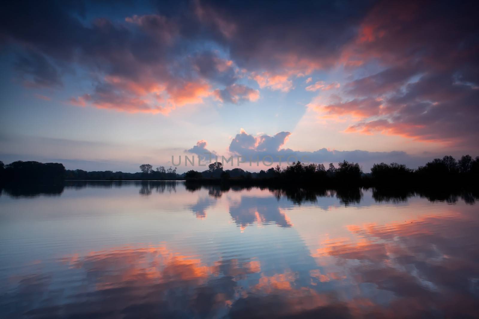 dramatic sky reflected in wild  lake at sunrise