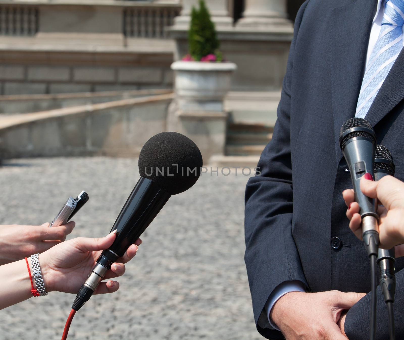 Interview with media microphone held in front of businessman, spokesman or politician