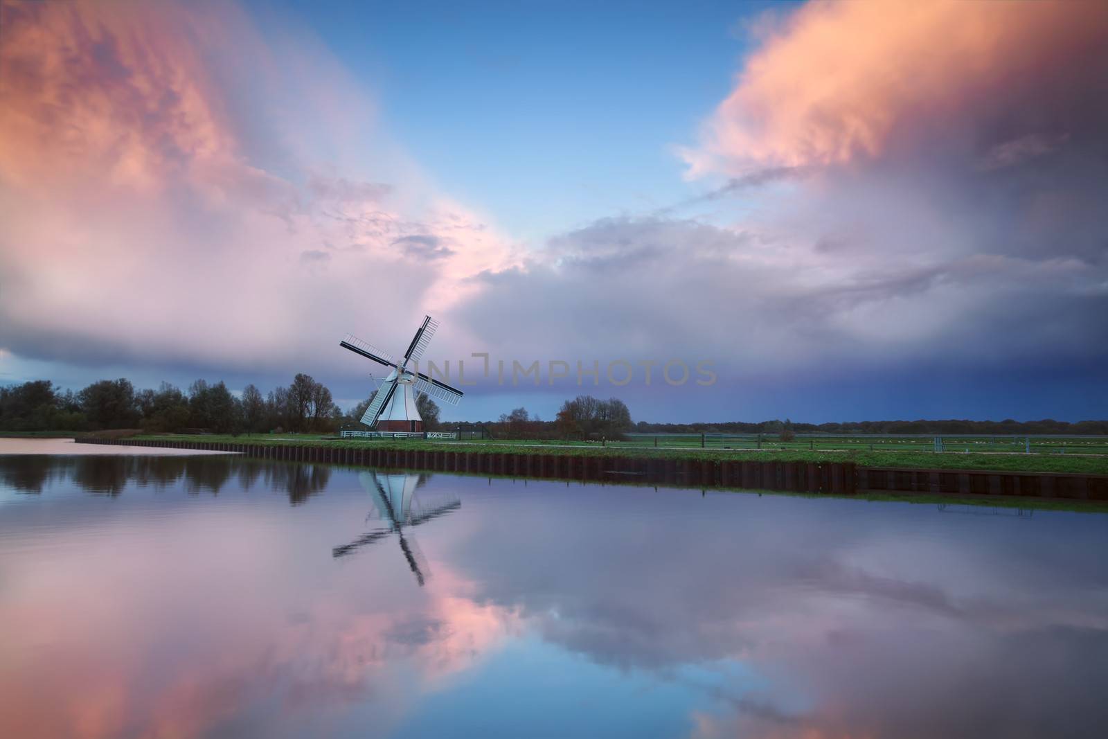 beautiful sunset over Dutch windmill by river, Netherlands