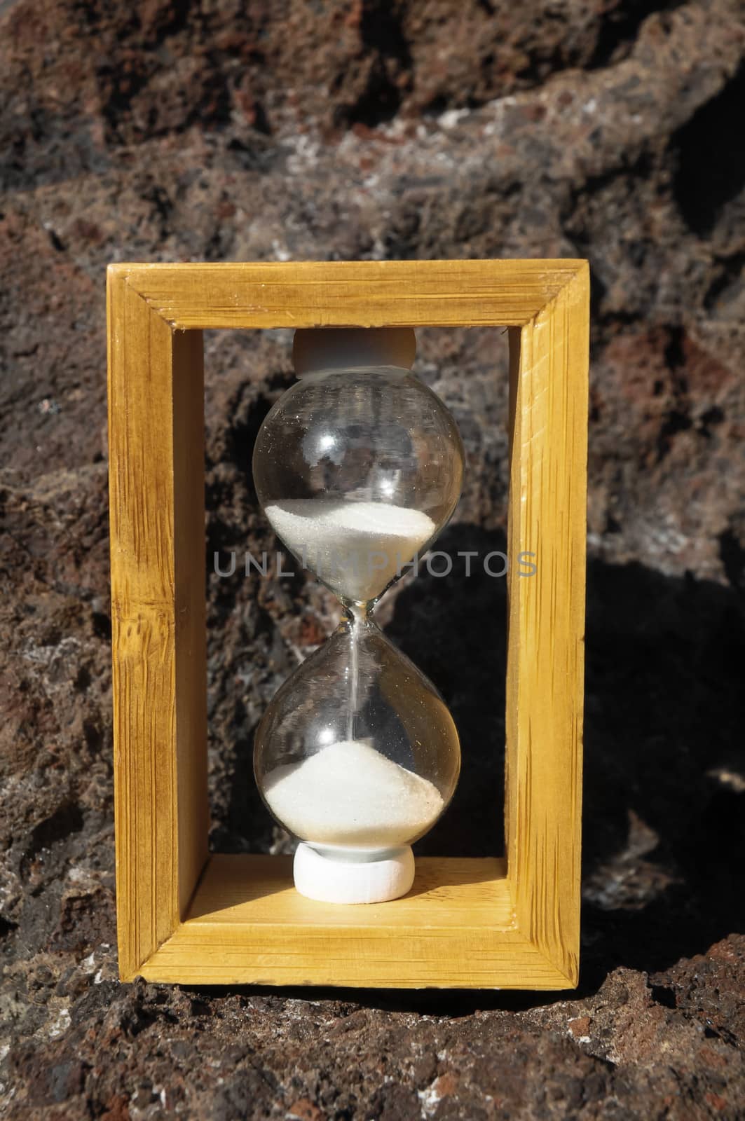 Time Concept White Sand Hourglass on the Volcanic Rocks