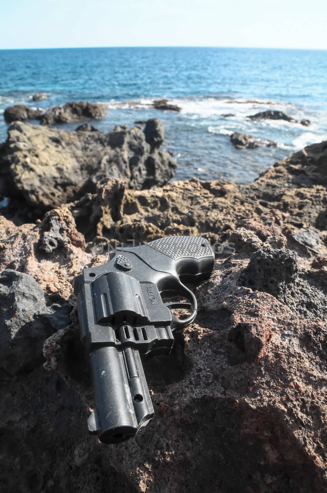 Plastic Revolver Gun Toy on the Volcanic Rocks