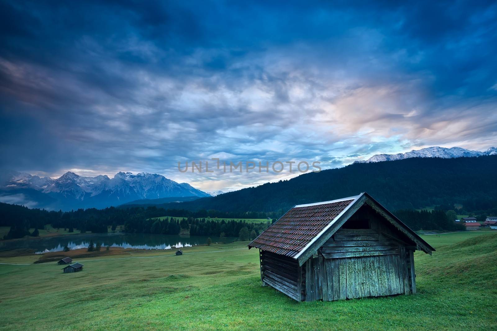 wooden hut by Geroldsee lake during rainy sunrise, Bavaria, Germany
