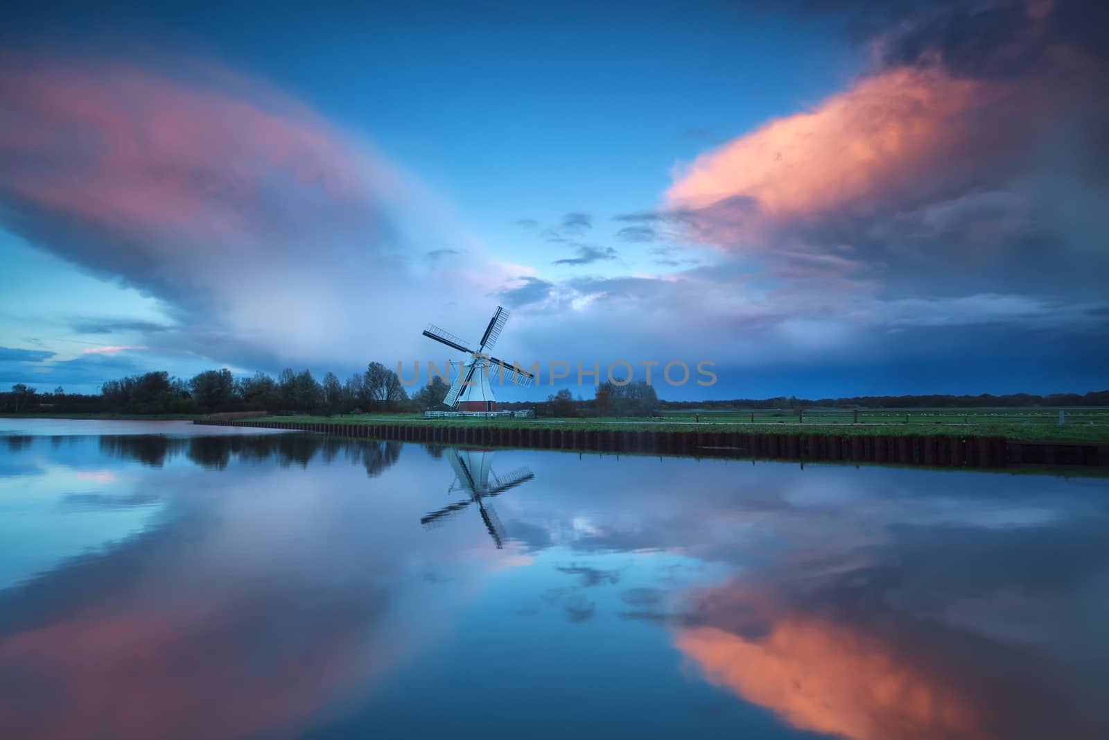 dramatic stormy sunset over Dutch windmill and river, Groningen, Netherlands