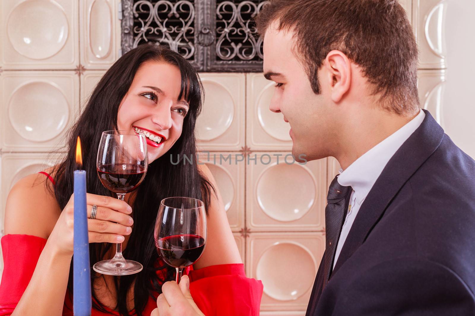 Loving young couple drinking red wine and smiling into each others eyes as they sit at a table in a restaurant enjoying a romantic date