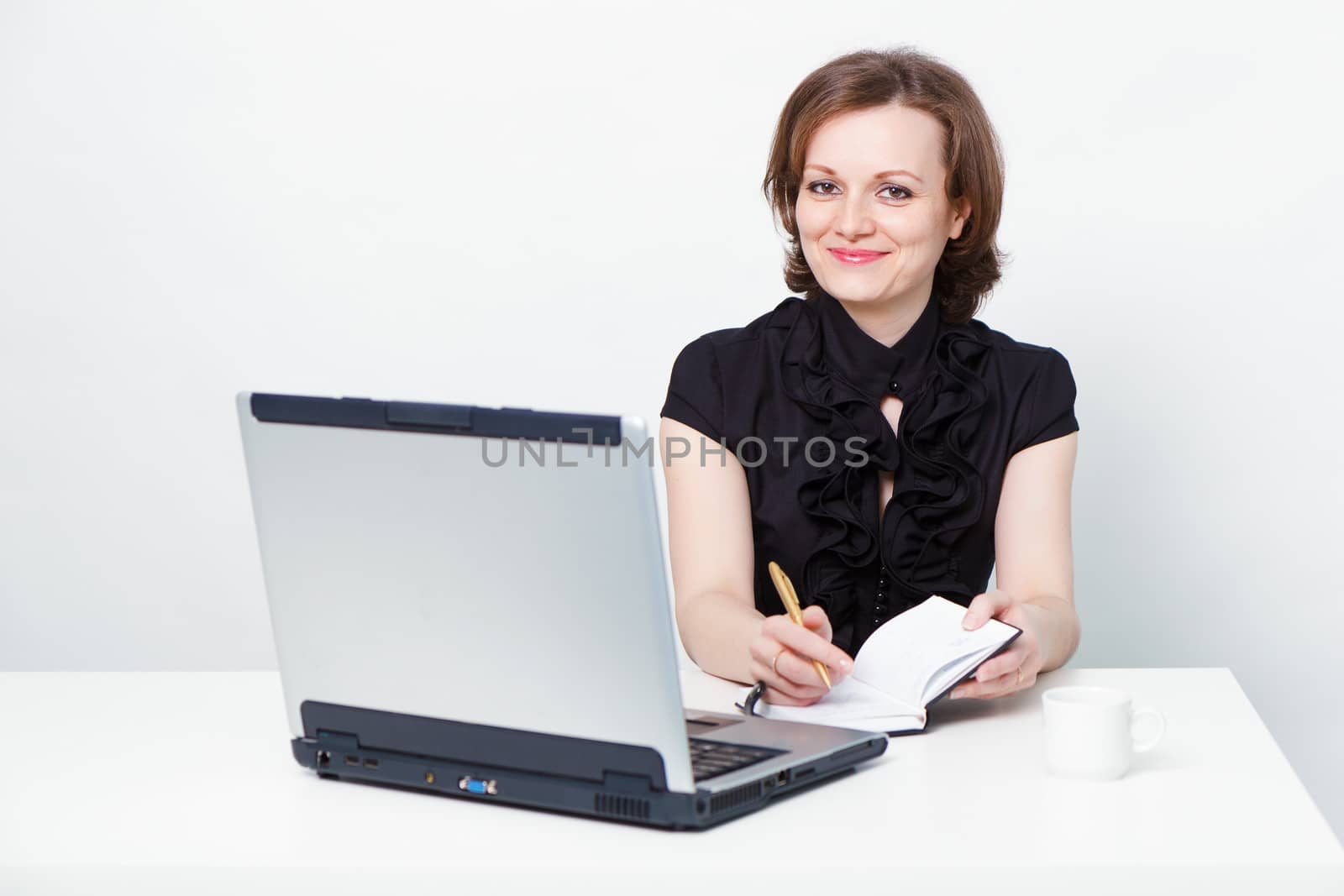 attractive girl in a black dress with a laptop at the table