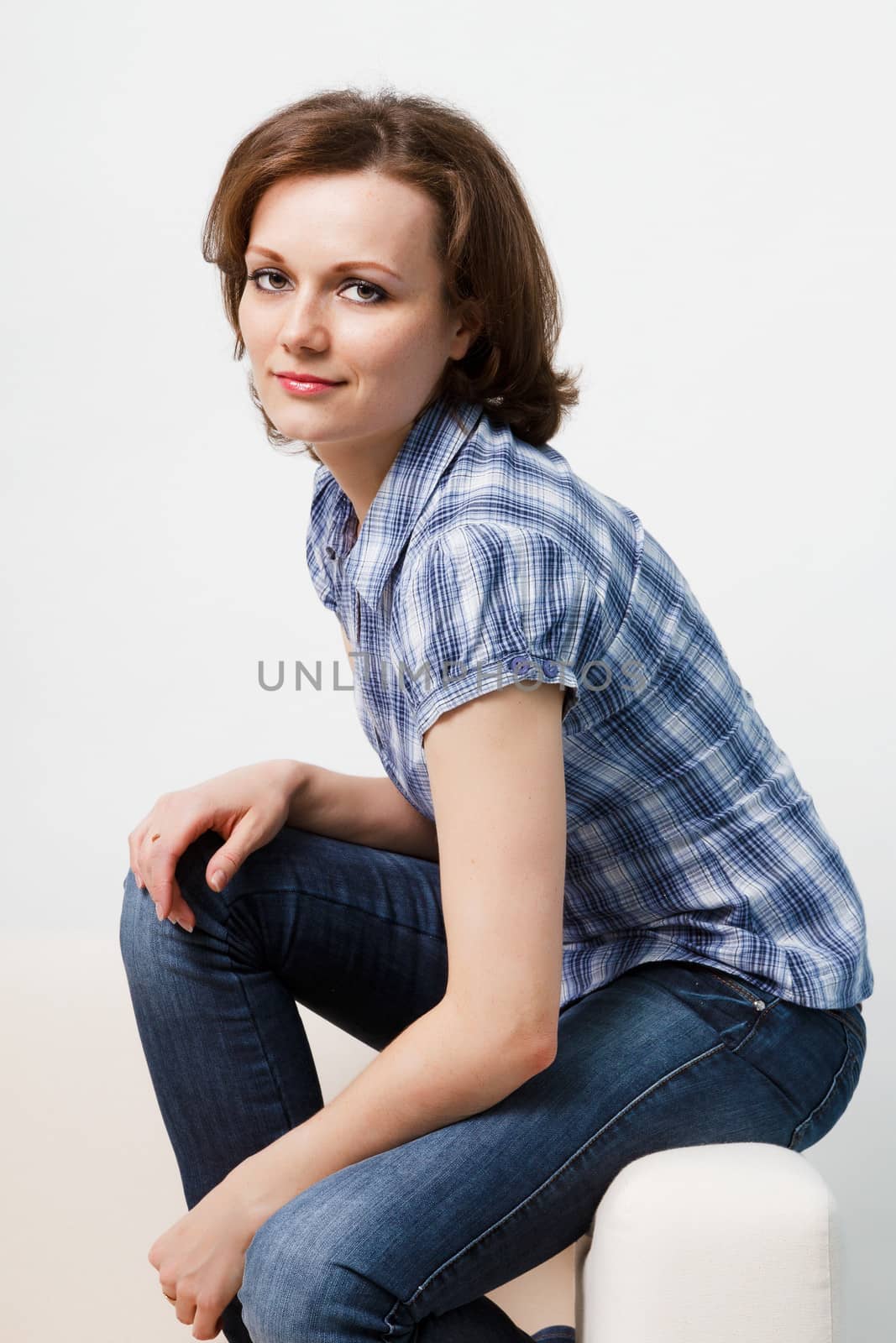 Sitting girl in a plaid shirt and jeans