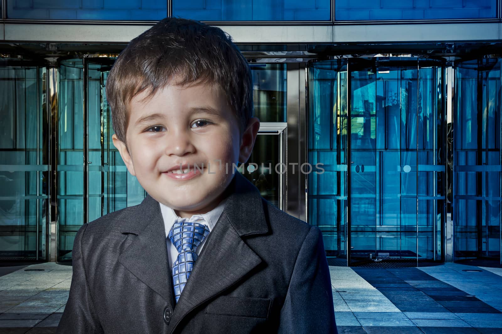 Modern child dressed businessman with hands in his tie and skysc by FernandoCortes
