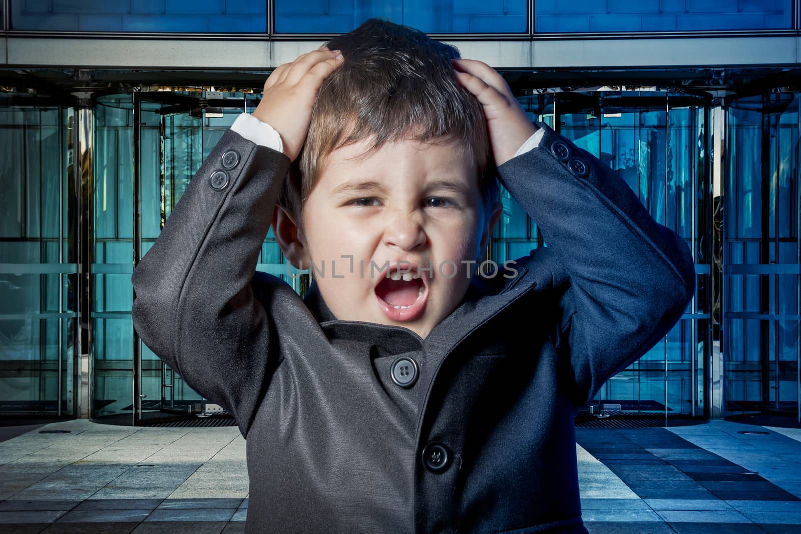 Serious child dressed businessman with hands in his tie and skyscrapers in the background