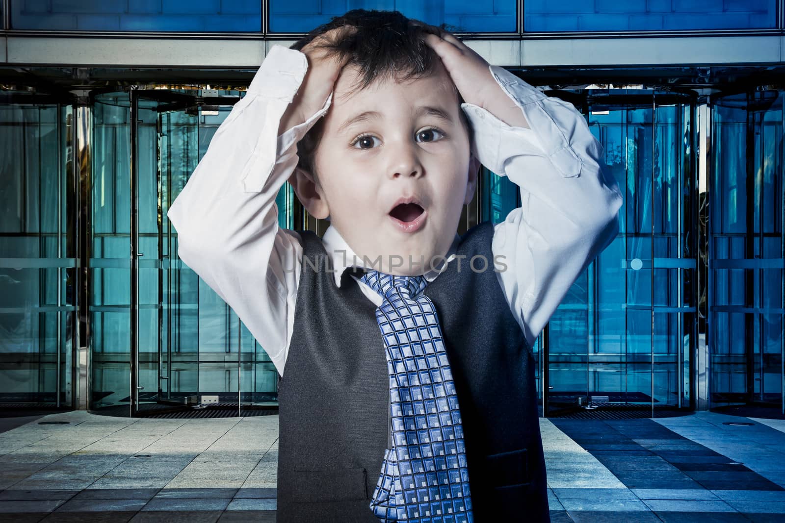 Fun, child dressed businessman with hands in his tie and skyscrapers in the background
