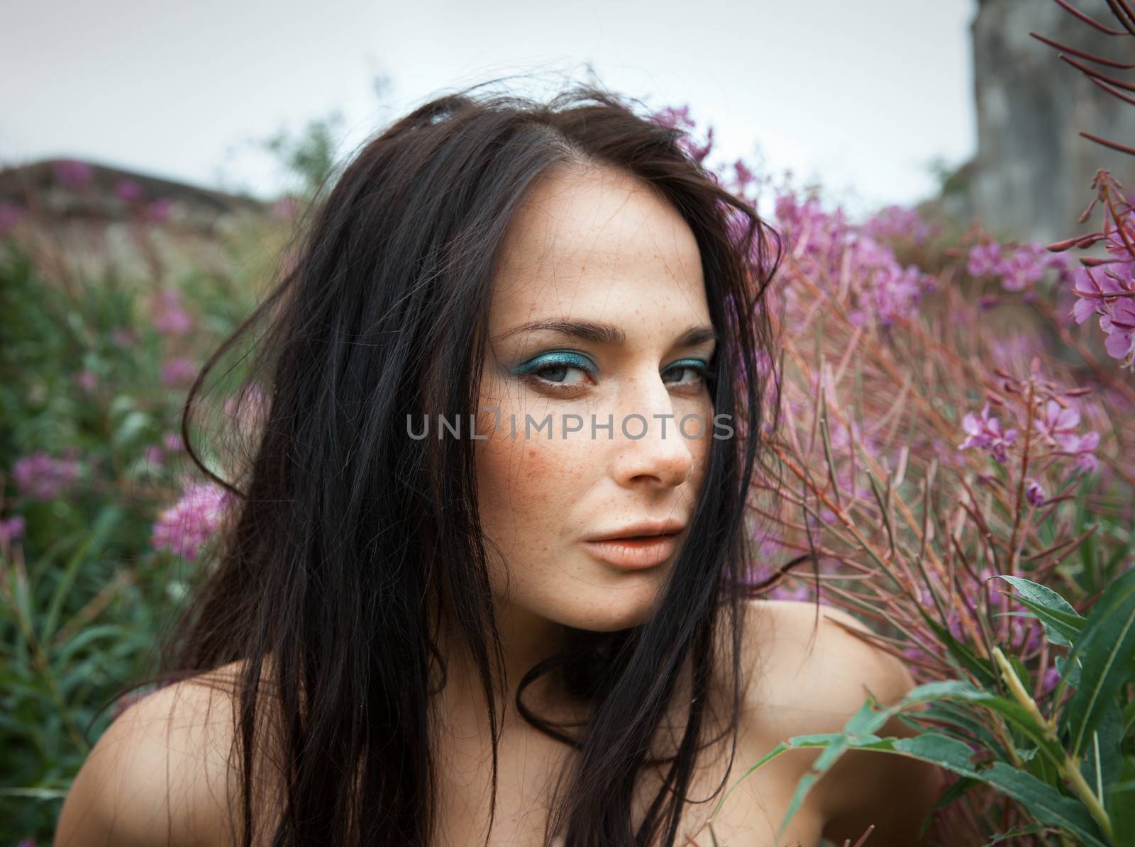 Seminude beautiful girl among the flowers and old concrete wall background