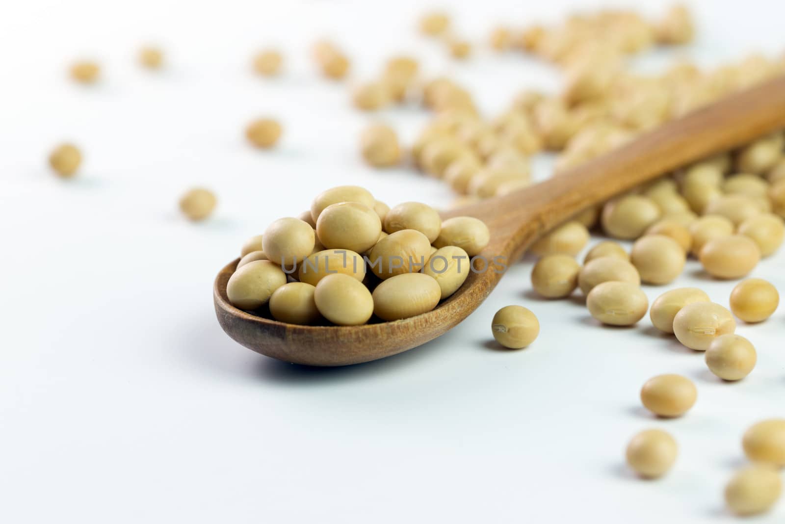 Close-up of soya beans on wooden spoon over white background