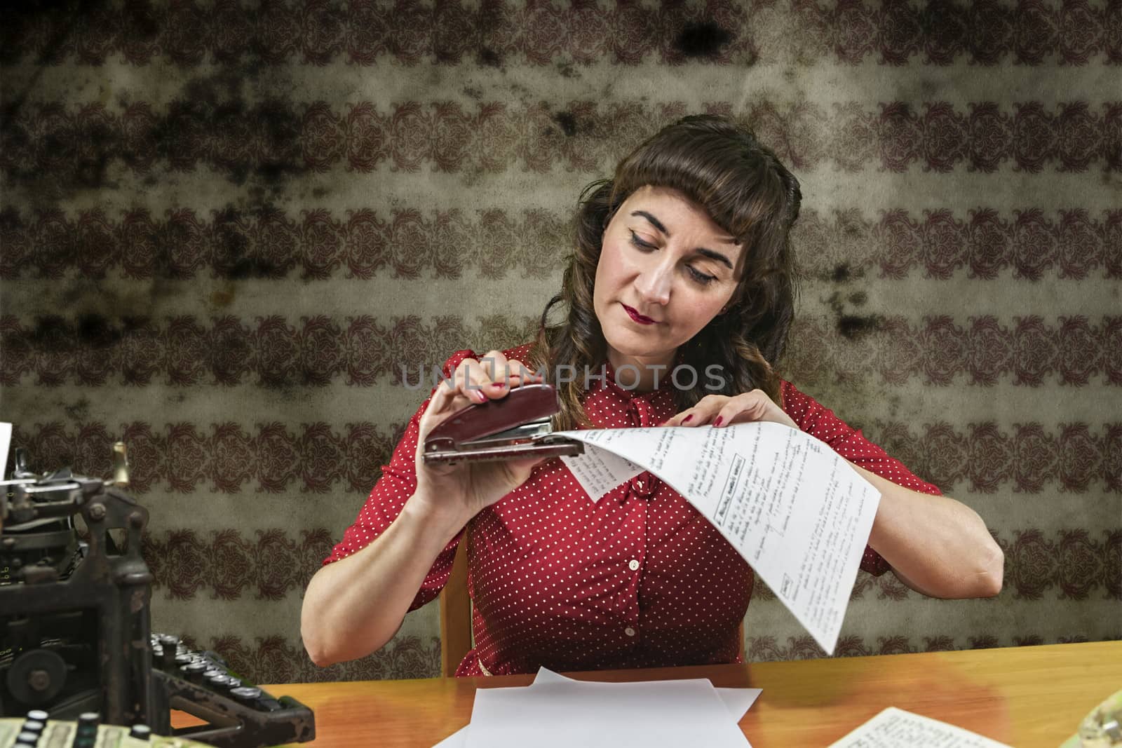 Young woman with red dress stapling papers in office, 1960's