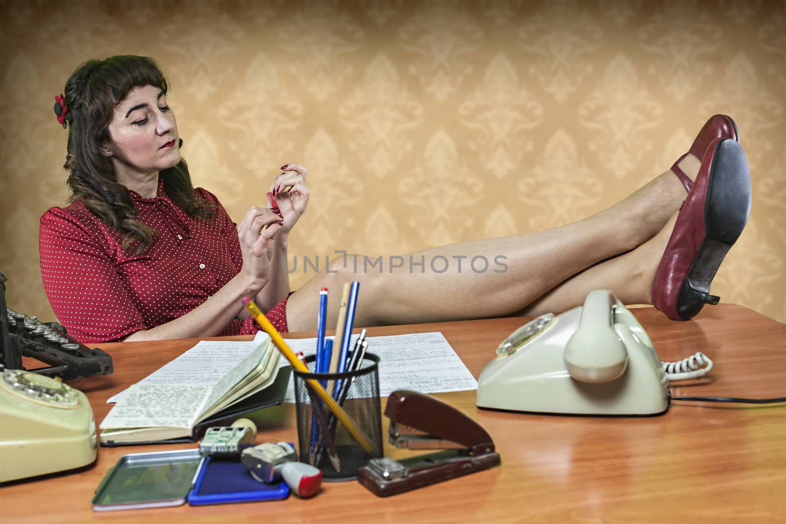 Young secretary with a nail file in the office, 1960's scene by digicomphoto