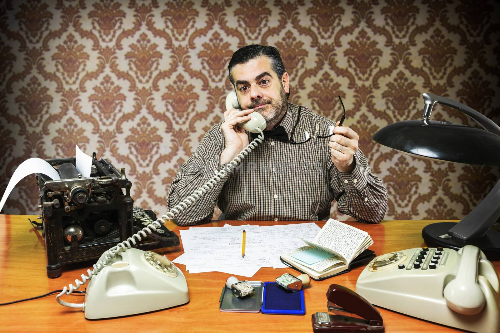 Employee with glasses talking on the phone in the office in the 1960s