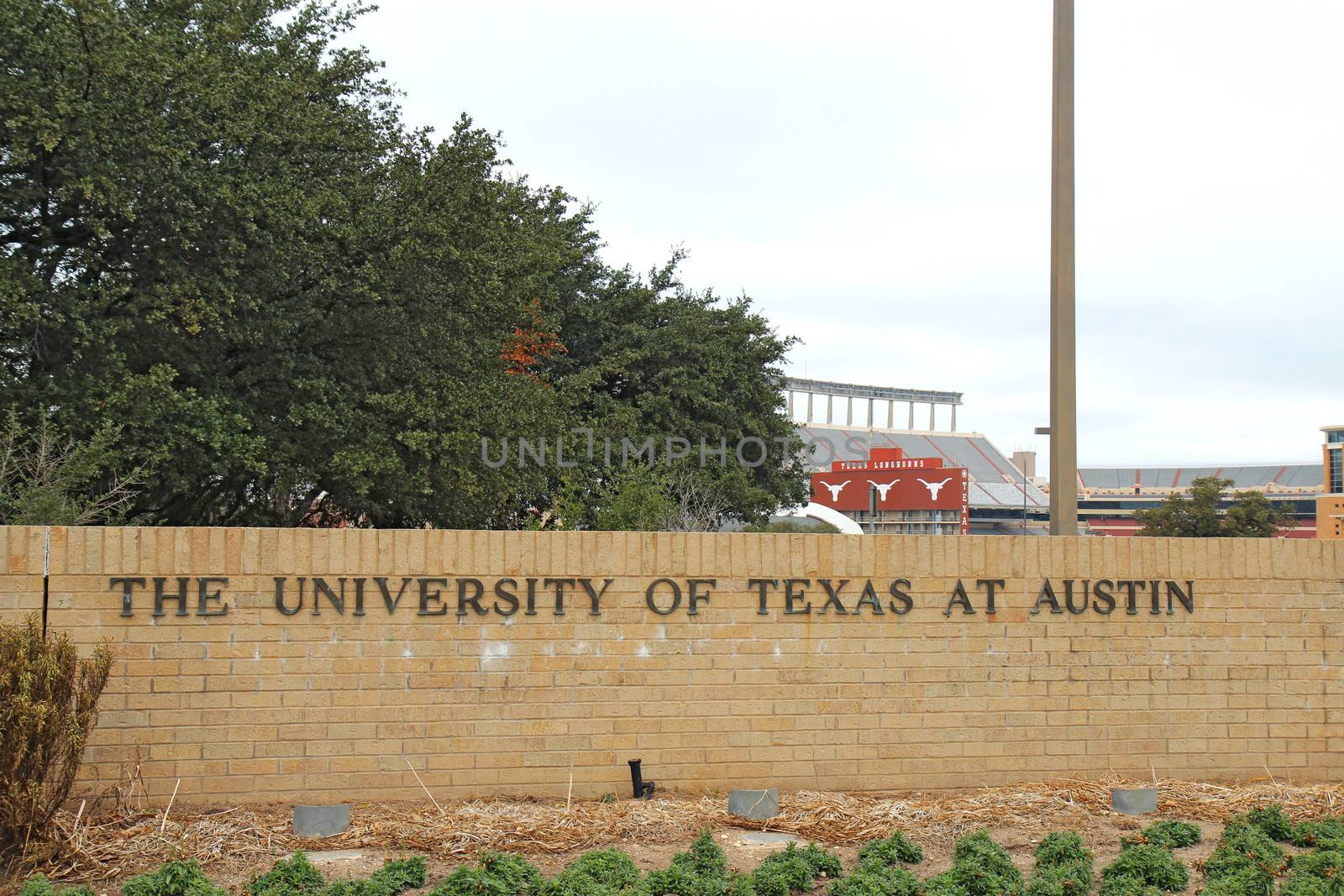 AUSTIN, TEXAS - FEBRUARY 2 2014: Sign for the University of Texas at Austin with Darrell K Royal-Texas Memorial Stadium in the background. Founded in 1883, it is one of the top 20 schools in the USA.