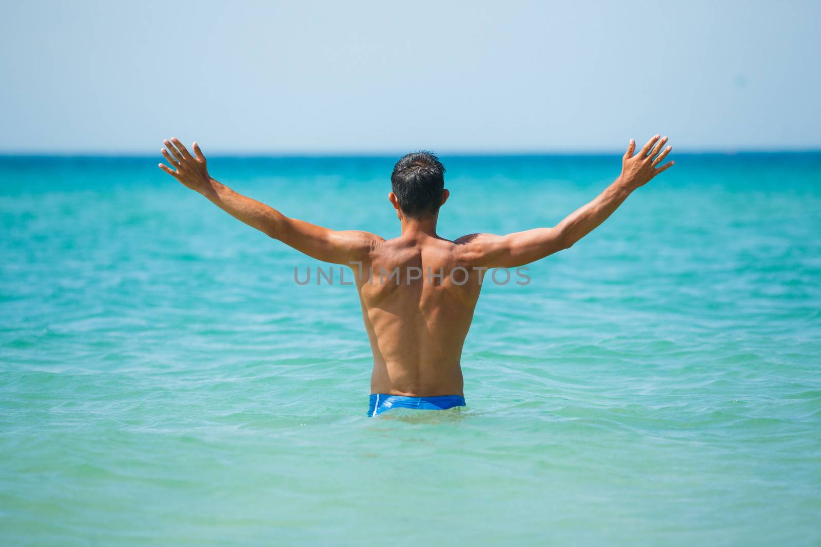 Back view of athletic young man on beach vacation