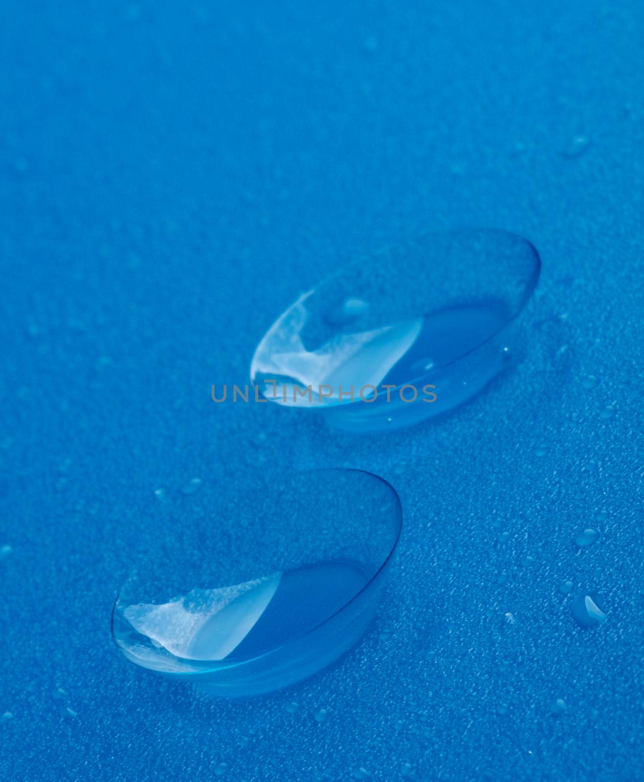 Two Contact Lenses with Water Droplets isolated on Blue background